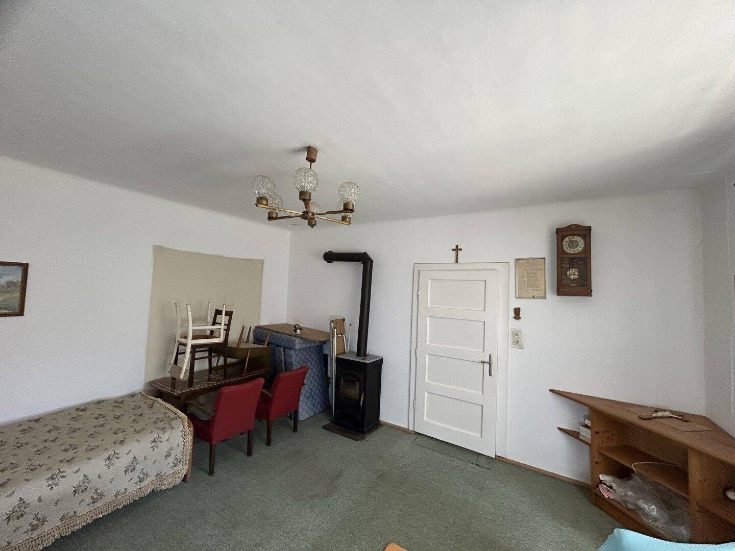Wohnzimmer mit Teppichboden, einem Holzofen und traditionellen Möbeln.