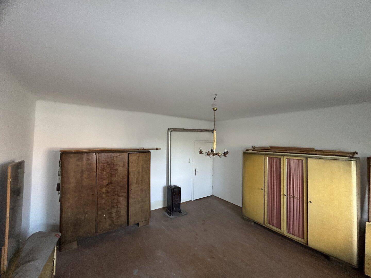 Geräumiges Schlafzimmer mit Holzboden, einem Holzofen und traditionellen Schränken.