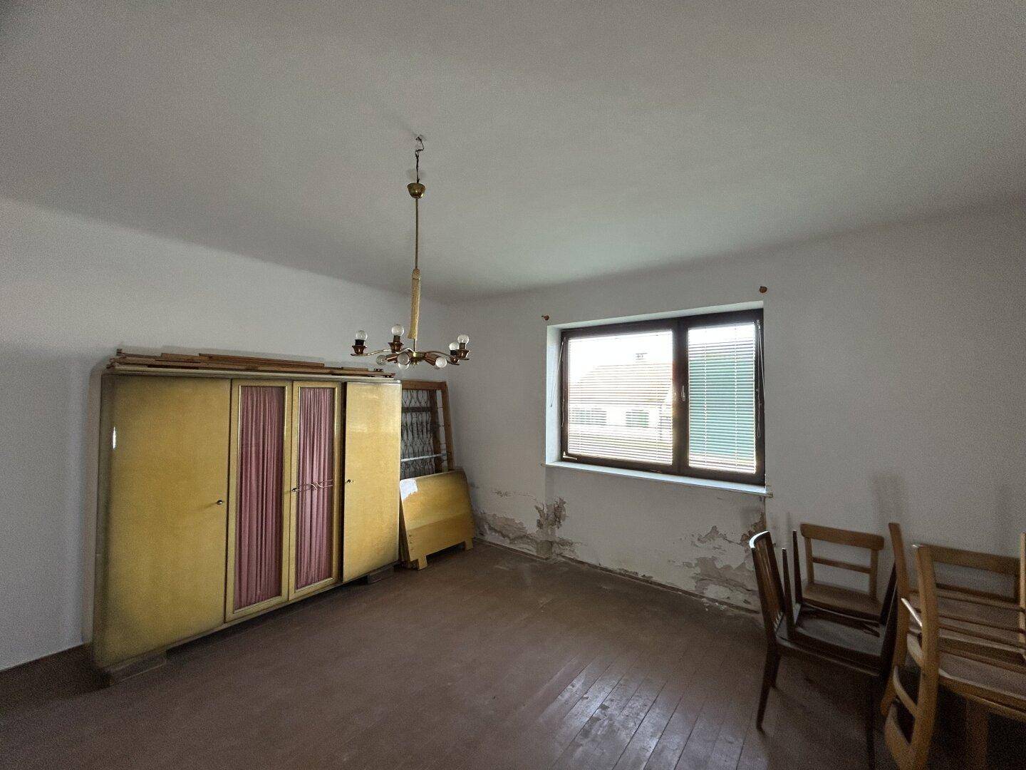 Schlafzimmer mit Holzboden, einem großen Fenster und traditionellen Möbeln.