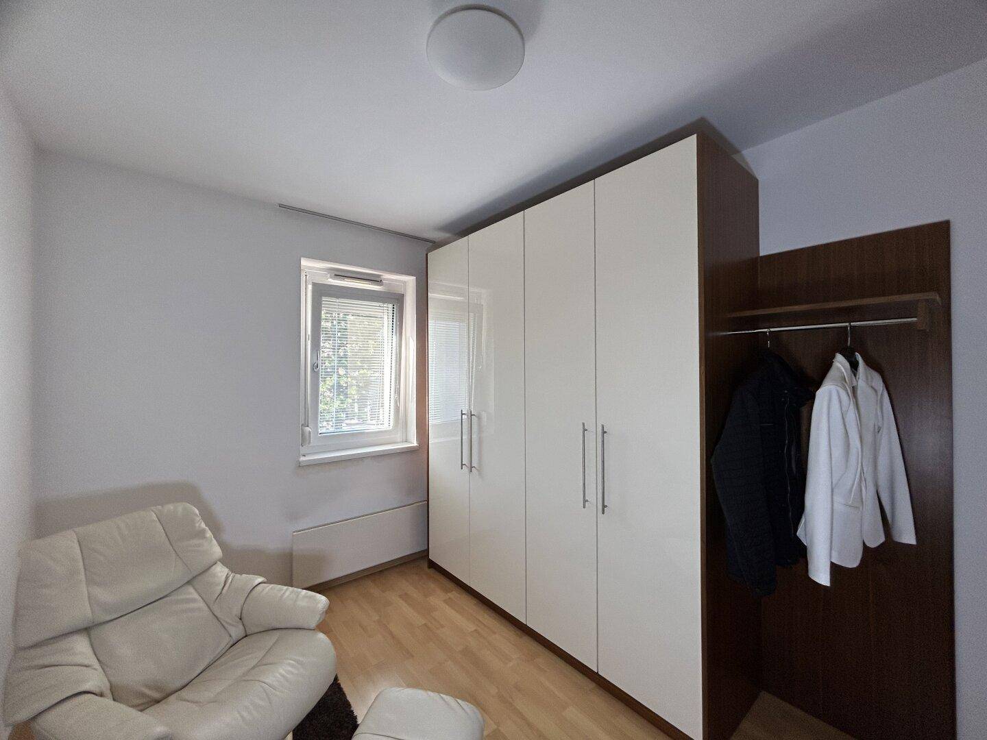 Zimmer mit großem Kleiderschrank und bequemem Sessel, ideal als Gäste- oder Arbeitszimmer.