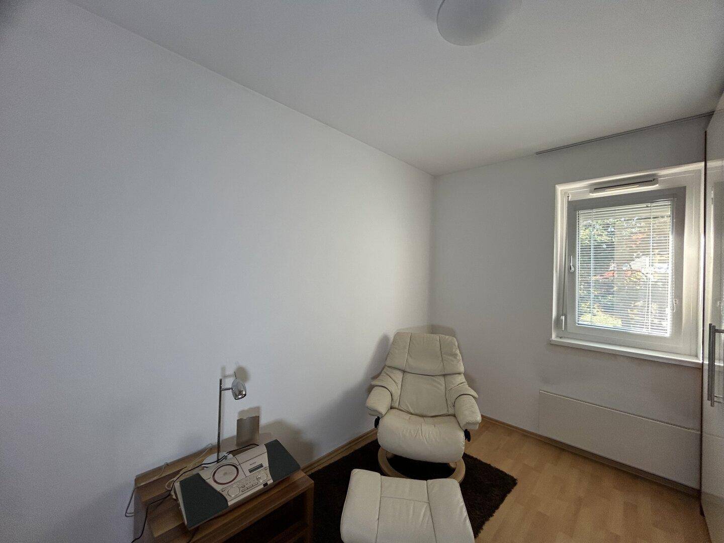 Helles Zimmer mit Sessel und Fenster, bietet einen ruhigen Rückzugsort.