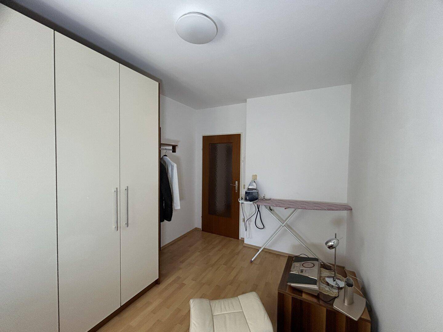Praktischer Raum mit Kleiderschrank und Bügelbrett, vielseitig nutzbar als Hauswirtschafts- oder Gästezimmer.