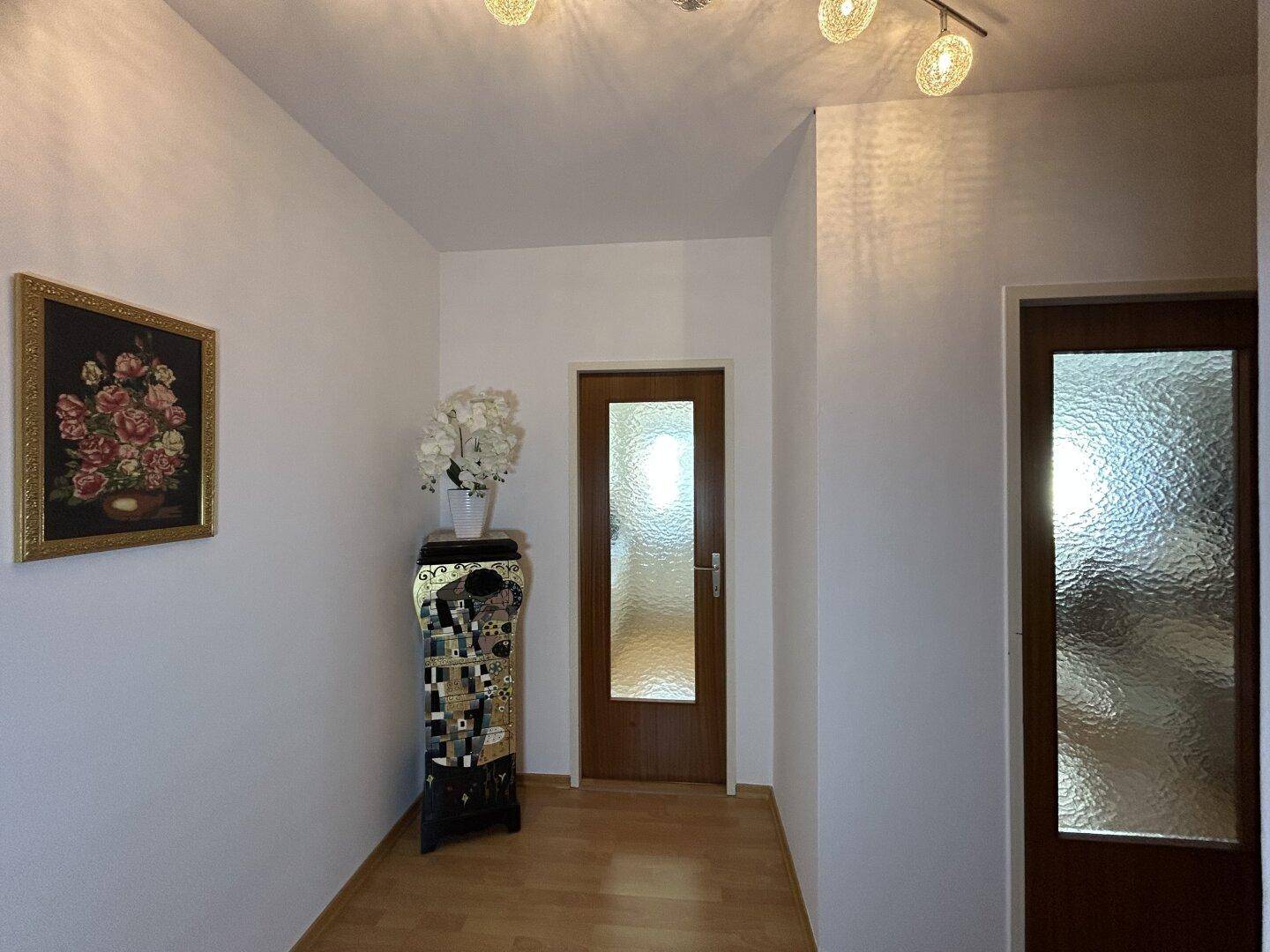 Flurbereich mit Kunstwerk und Blumendekoration, schafft eine wohnliche Atmosphäre.