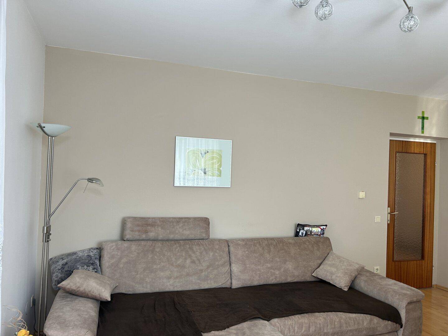 Gemütliches Wohnzimmer mit großem Sofa und Stehlampe, bietet Platz zum Entspannen.