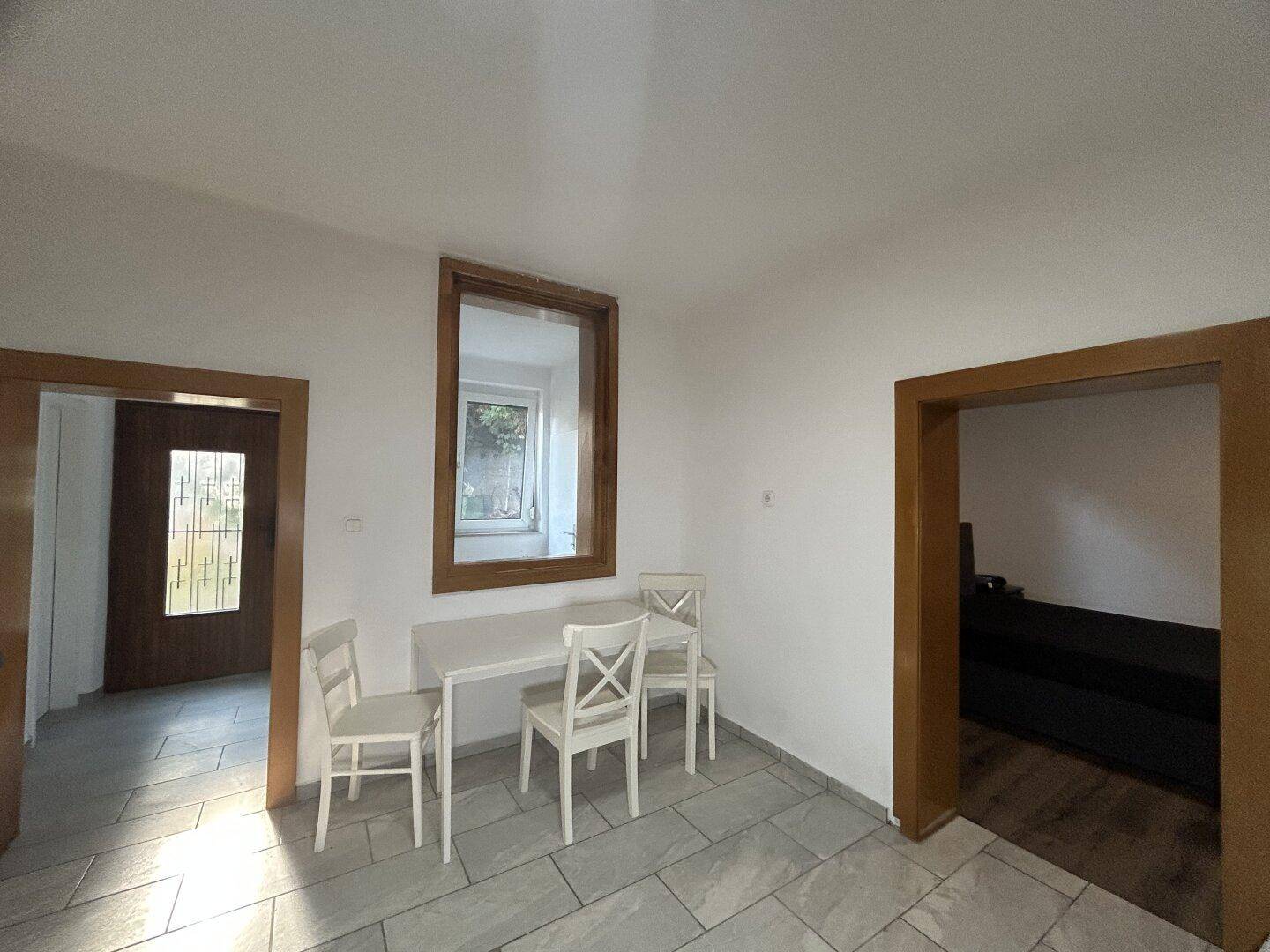 Heller Essbereich mit Fliesenboden, Esstisch und Durchgängen zu angrenzenden Zimmern.