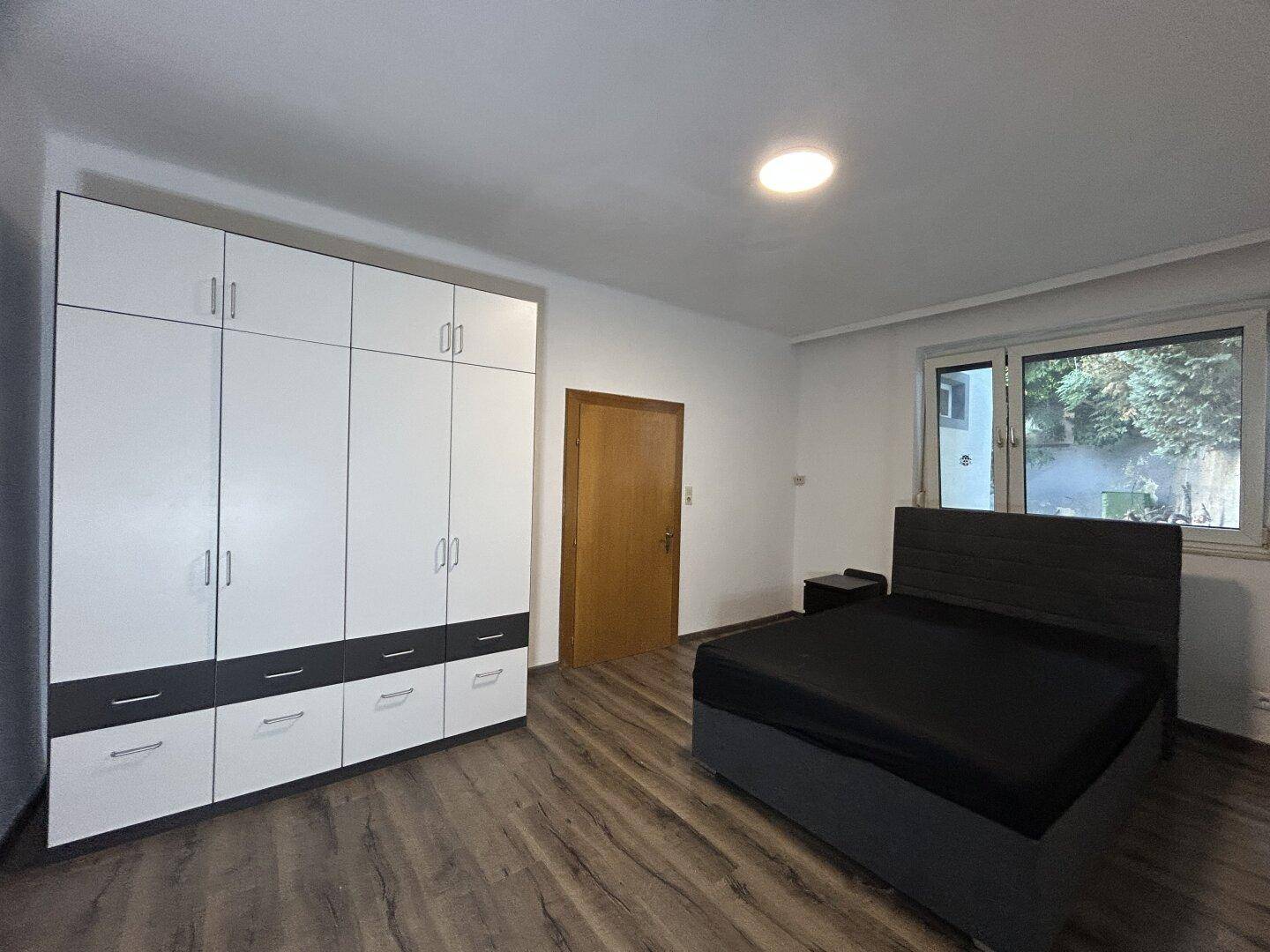 Schlafzimmer mit modernem Bett, großem Kleiderschrank und Laminatboden.