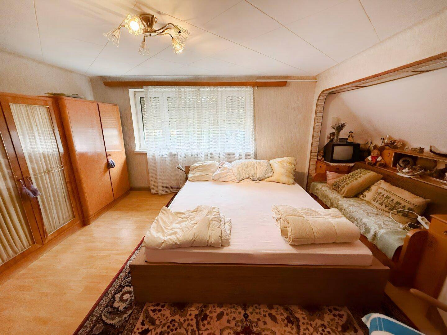 Schlafzimmer mit Doppelbett, Holzmöbeln und Dachschräge.