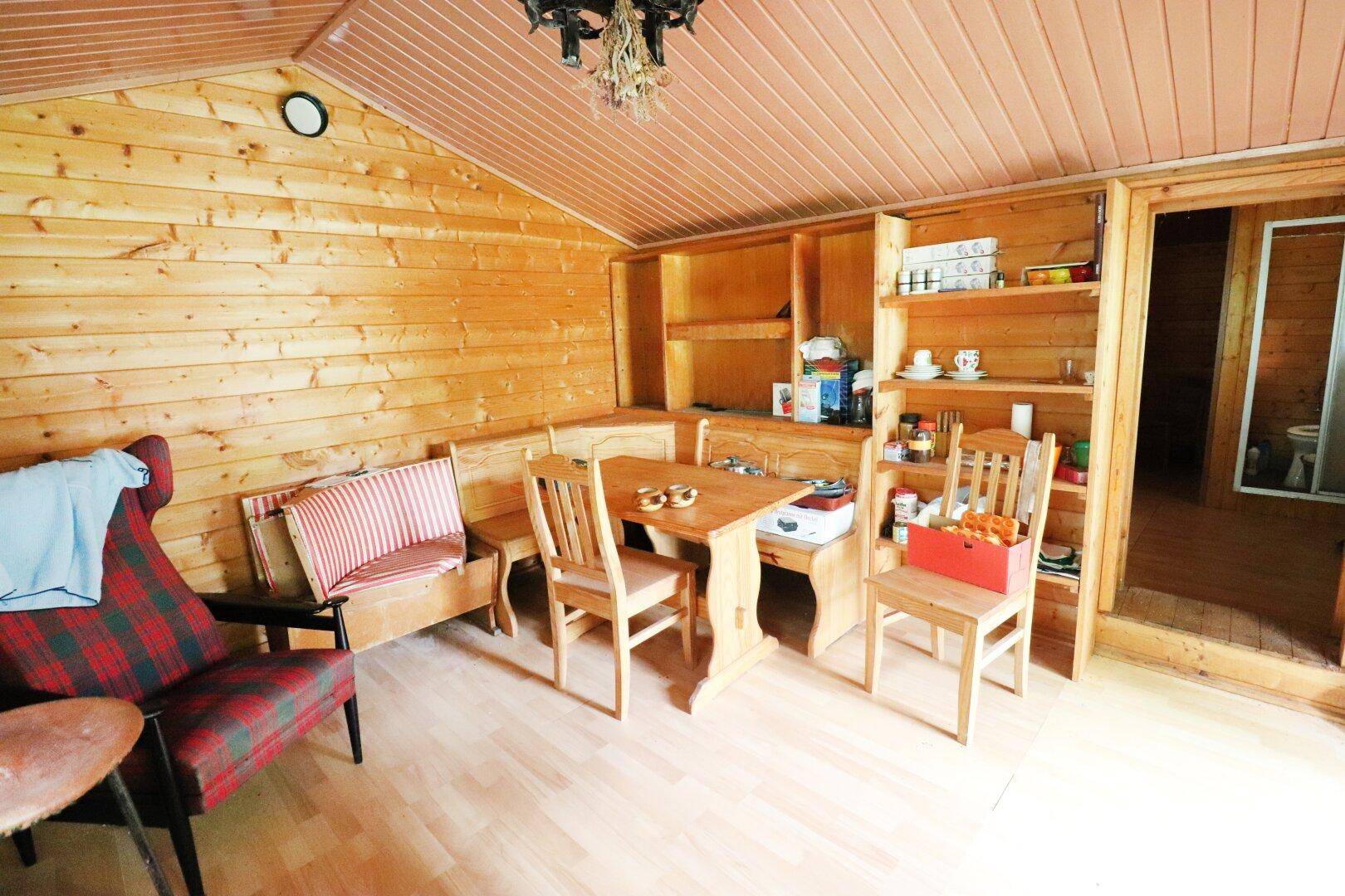 Rustikaler Wohn- und Essbereich mit Holzvertäfelung, eingebauten Regalen und einem Esstisch.