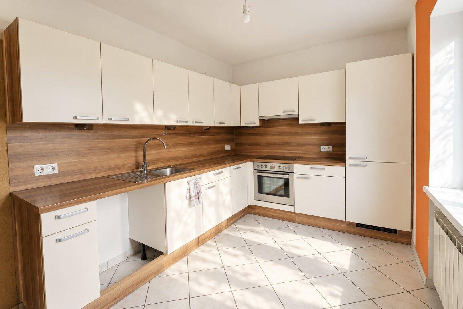 Moderne Einbauküche mit weißen Schränken, Holzoptik-Arbeitsplatten und Fliesenboden.