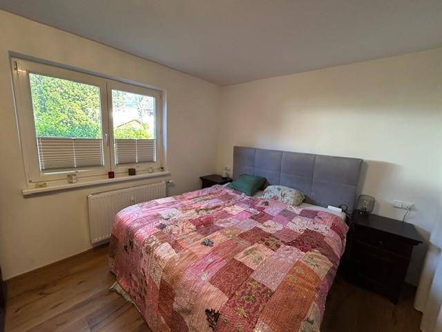 Helles Schlafzimmer mit Doppelbett, Nachttischen und Blick ins Grüne.
