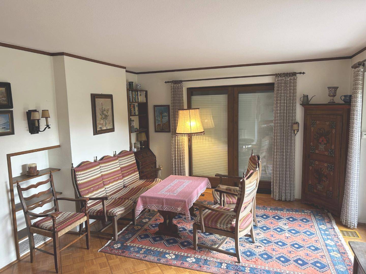 Traditionell eingerichtetes Wohnzimmer mit Holzboden und farbenfrohem Teppich.