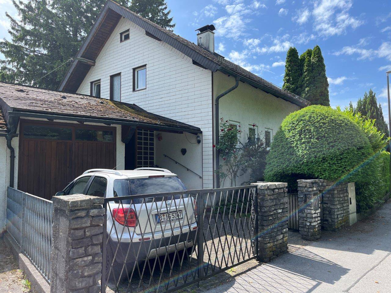Seitenansicht des Hauses mit Einfahrt, Carport und gepflegter Hecke.