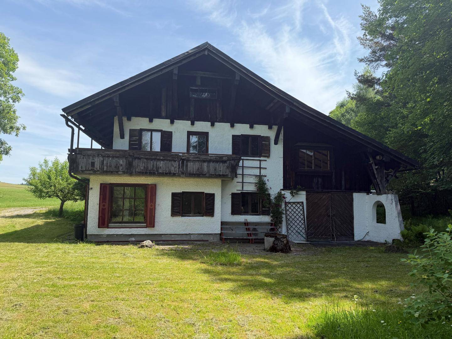 Charmantes Landhaus mit sichtbaren Holzbalken und großem Gartenbereich unter blauem Himmel.