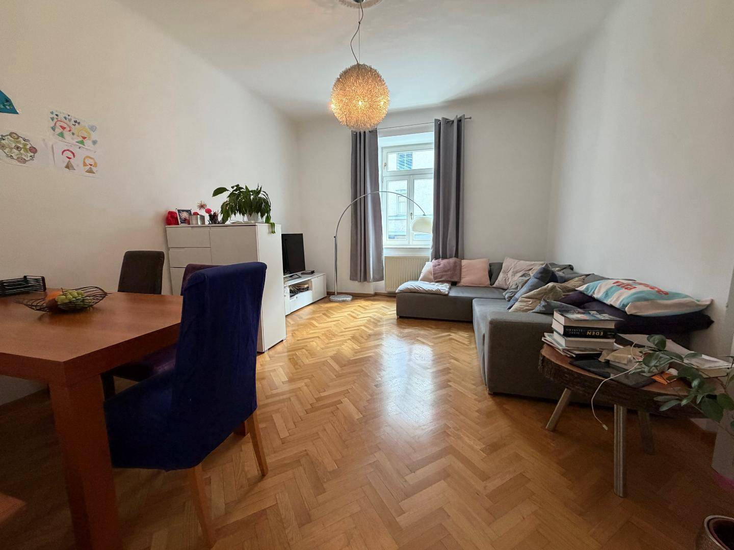 Gemütlicher Wohn-Essbereich mit Fischgrätparkett, Sofa und Esstisch in hellem Ambiente.