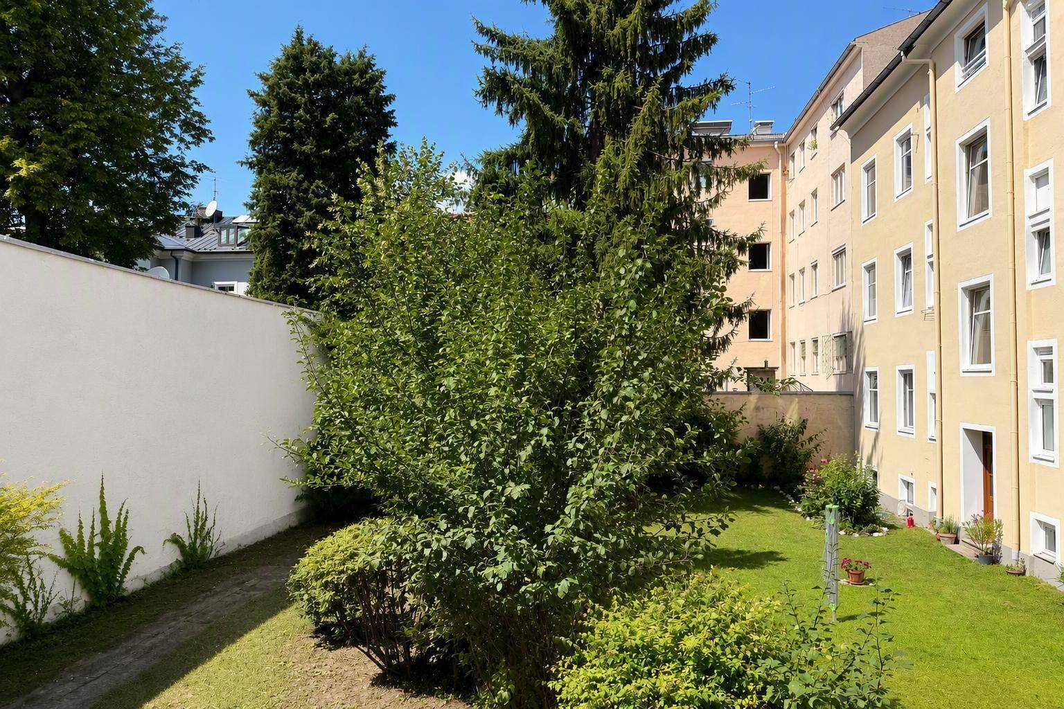 Gepflegter Gartenbereich mit Rasenfläche und Sträuchern neben dem Wohngebäude.