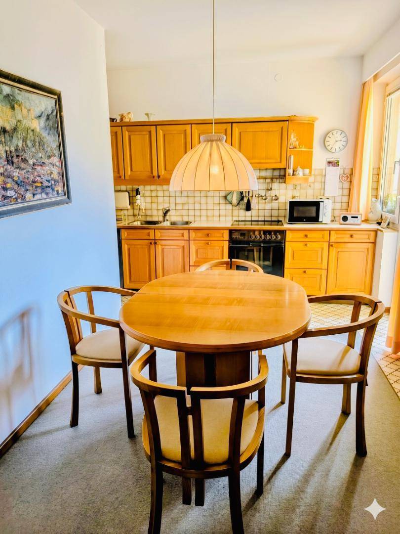 Gemütliche Wohnküche mit Holzeinbauten, einem runden Esstisch und traditionellen Fliesen an der Wand.