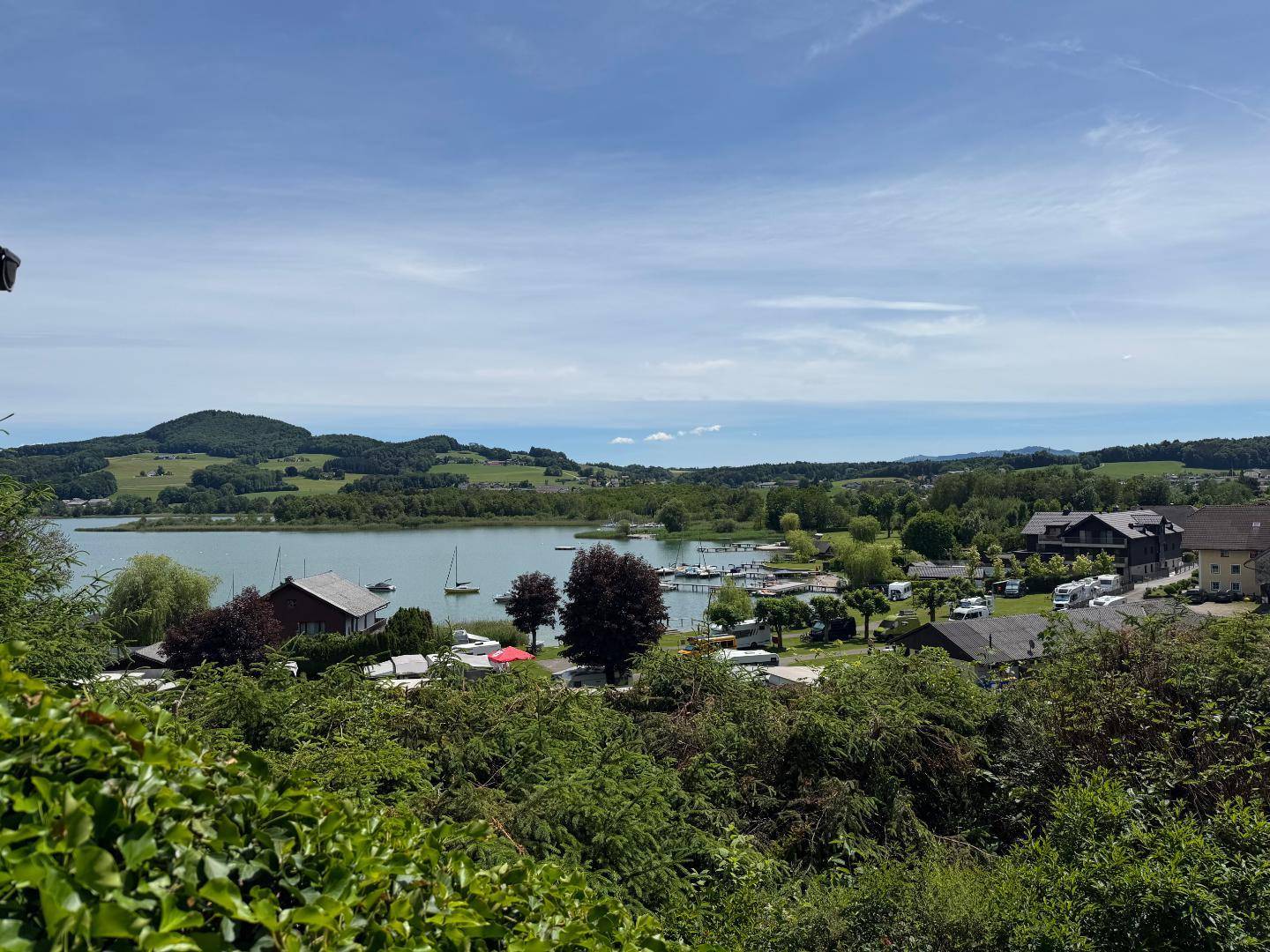Weitläufiger Panoramablick über den See, einen kleinen Hafen und die idyllische Landschaft.