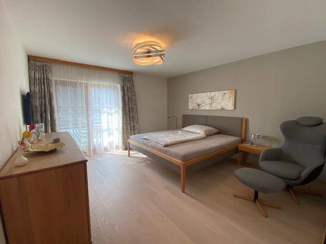 Helles Schlafzimmer mit Holzboden, Doppelbett und Zugang zum Balkon.