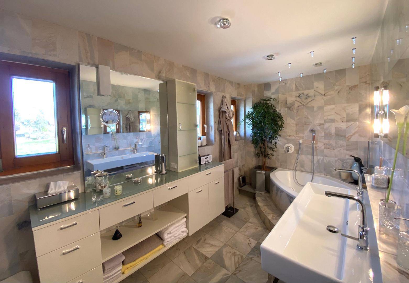 Geräumiges Badezimmer mit Badewanne, Fenster und eleganten Marmoroberflächen.