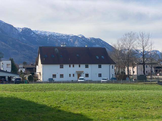Weißes Wohnhaus mit Satteldach vor einer beeindruckenden Bergkulisse.