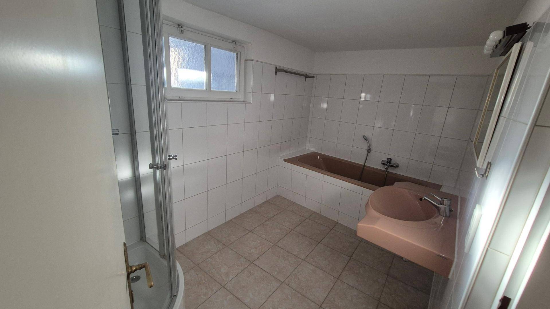 Badezimmer mit Duschkabine, Badewanne und Waschbecken in einem älteren, aber funktionalen Zustand.