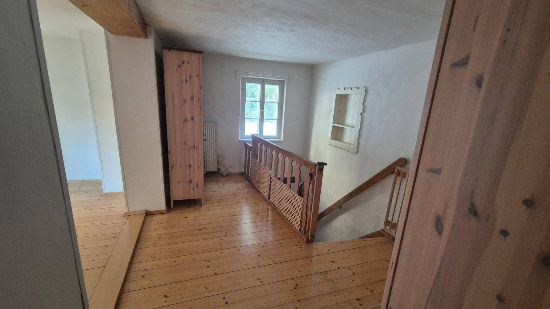 Heller Flur mit Holzboden, Holzgeländer und einer Treppe, die die verschiedenen Ebenen verbindet.