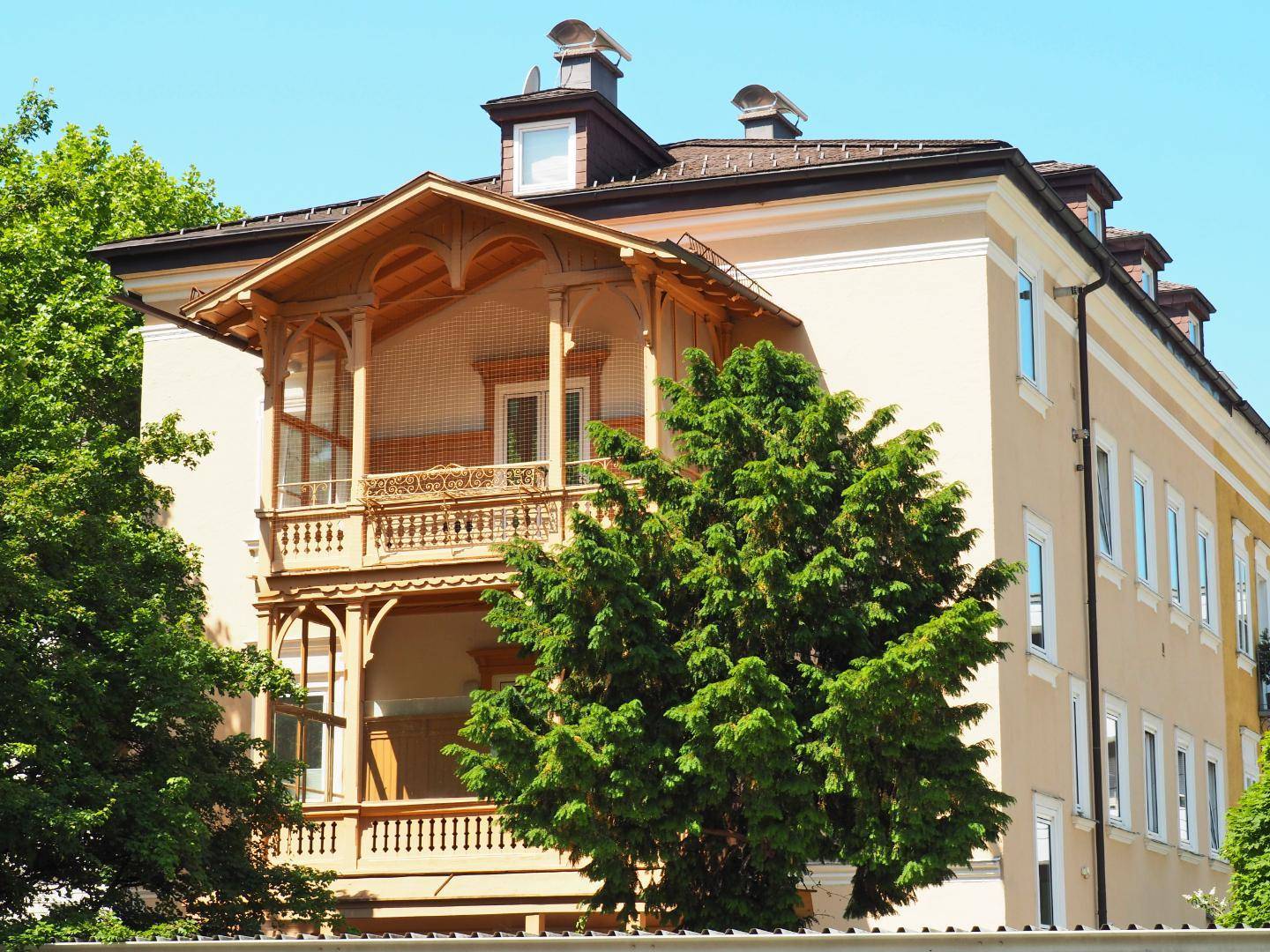 Historisches Gebäude mit einer markanten hölzernen Balkonkonstruktion und traditioneller Architektur unter blauem Himmel.