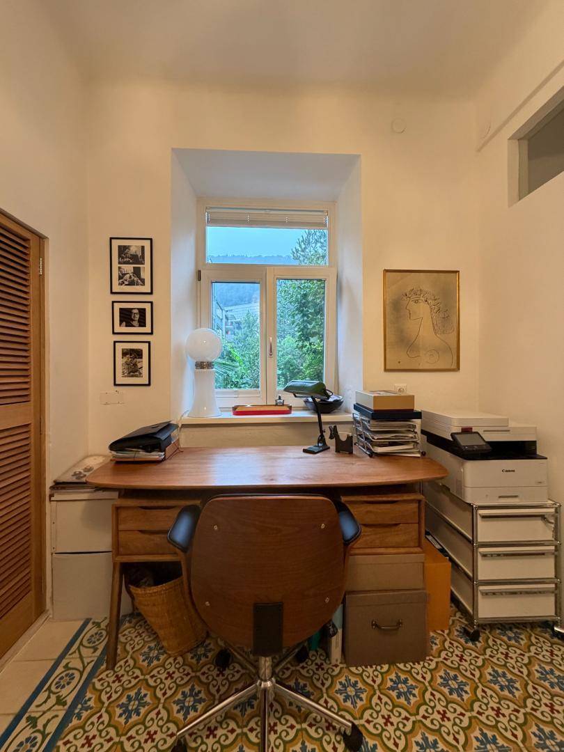 Gemütliches Arbeitszimmer mit Holzschreibtisch, Bürostuhl und einem Fenster mit Blick ins Freie.