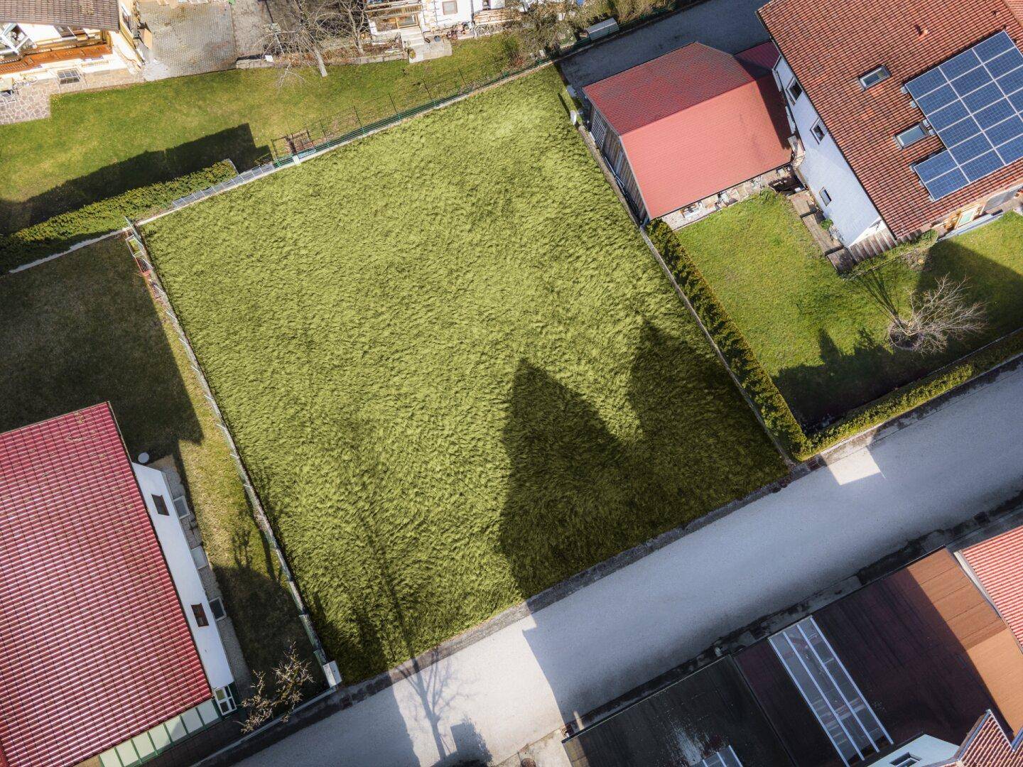 Luftaufnahme eines großen, grünen Grundstücks umgeben von Wohnhäusern und einer Straße.