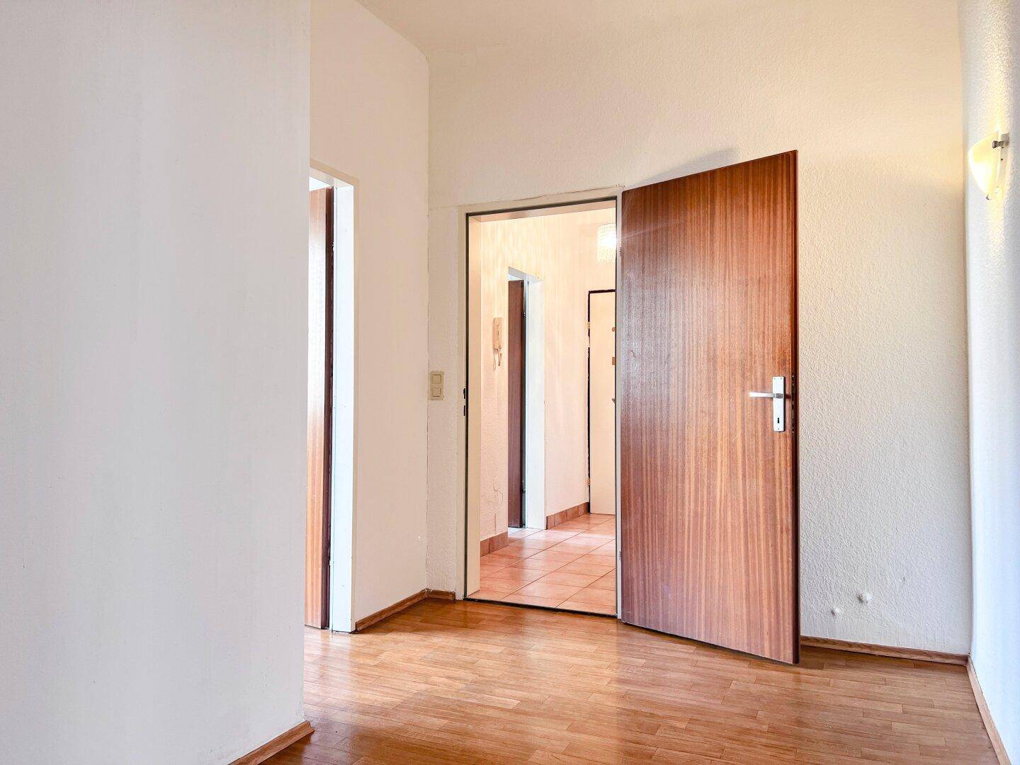 Flur mit Holztüren und Parkettboden, der zu weiteren Räumen führt.