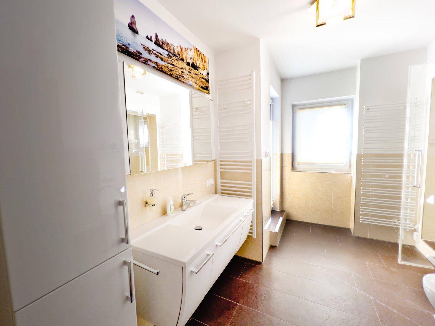 Modernes Badezimmer mit Einzelwaschbecken, Spiegelschrank, Handtuchheizkörpern und Fenster.