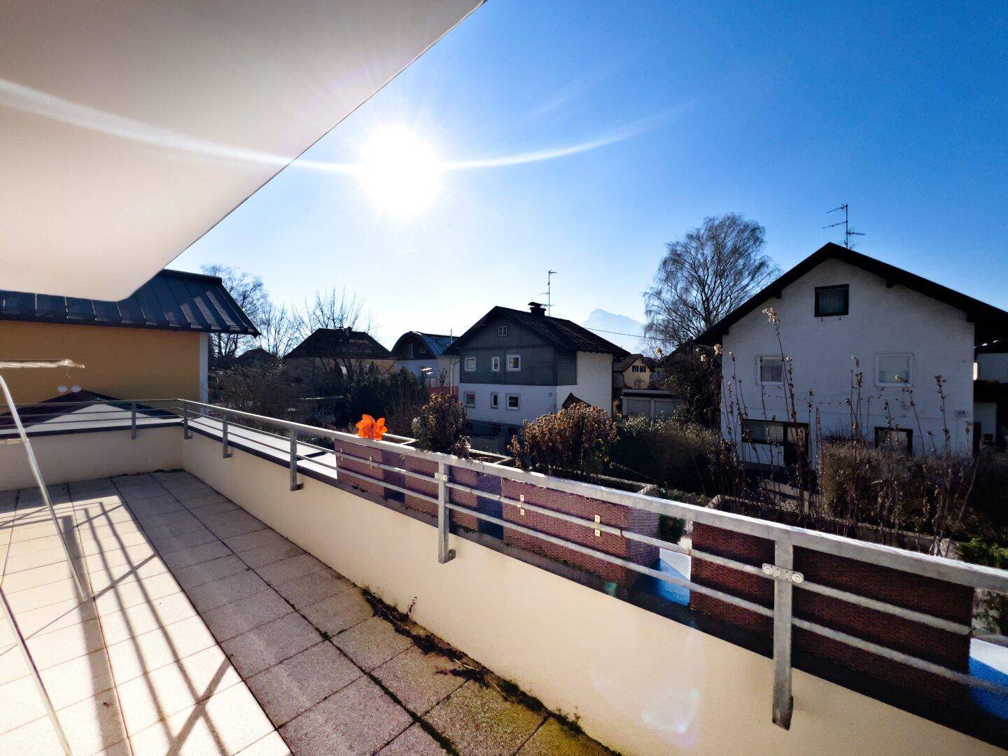 Sonniger Balkon mit Fliesenboden und weitem Blick über die Dächer der Nachbarschaft.