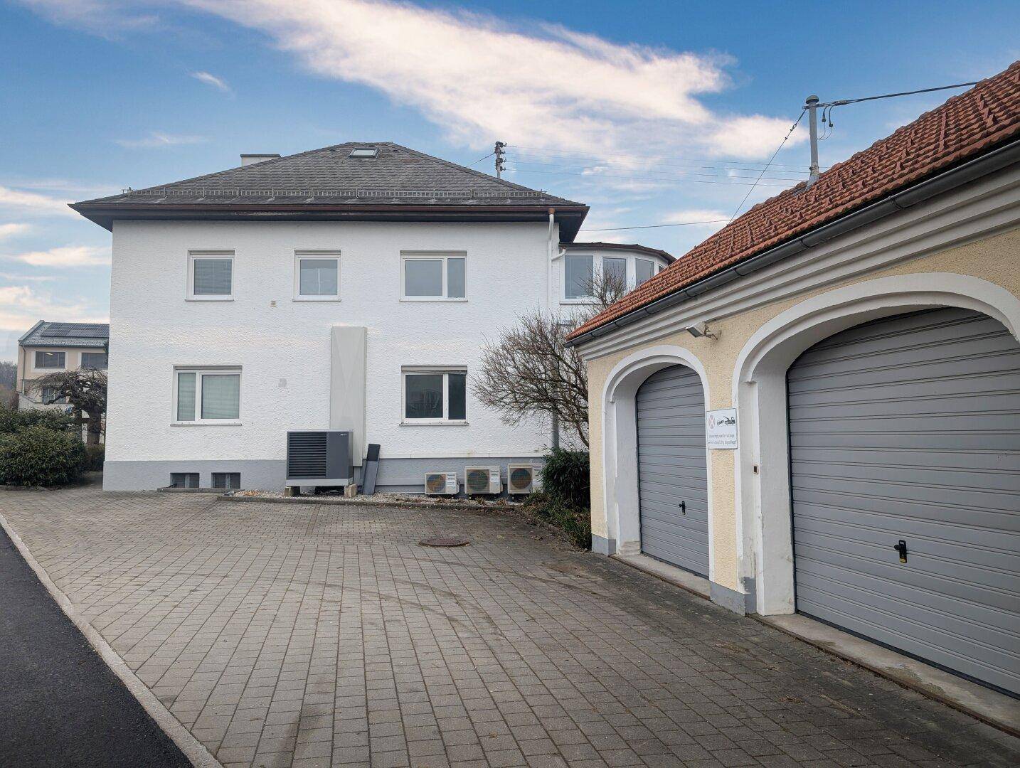 Rückansicht des weißen Hauses mit Außeneinheiten und einer weiteren Garage.