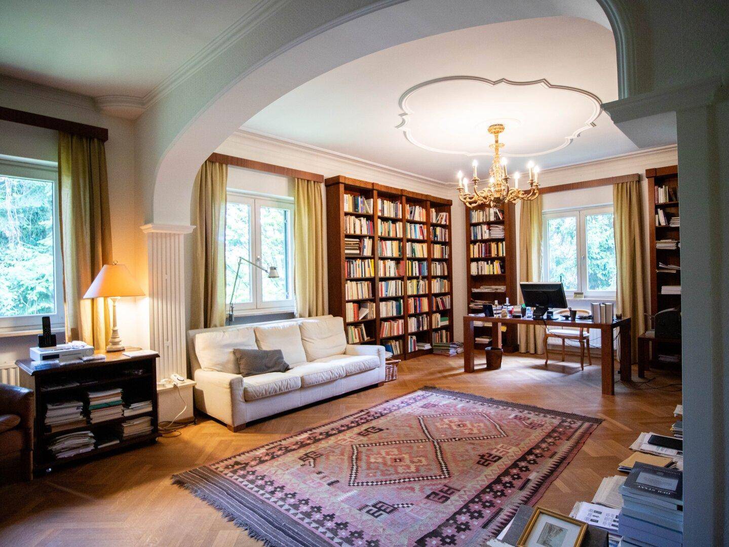 Elegantes Arbeitszimmer mit hohen Bücherregalen, Parkettboden und Kronleuchter.