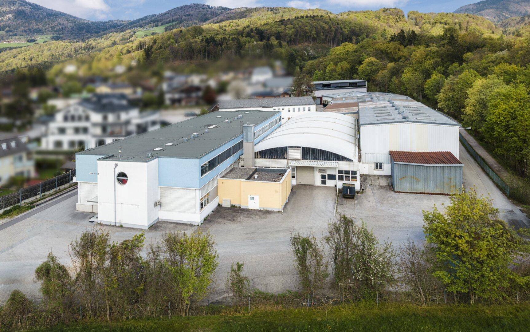 Übersichtsaufnahme des Gewerbekomplexes aus der Vogelperspektive mit verschiedenen Hallen und Dächern.