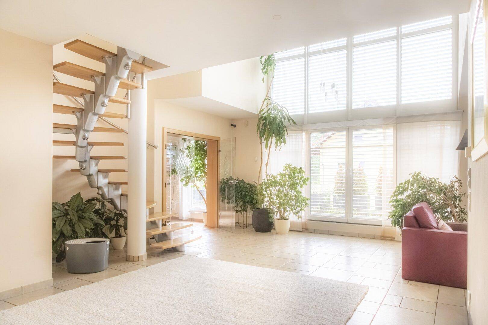 Geräumiger Eingangsbereich mit Wendeltreppe, großen Fenstern und viel Tageslicht, offen gestaltet.