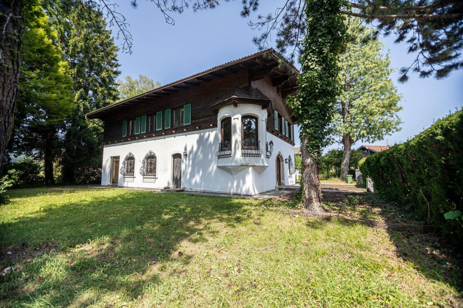 Großzügiger Gartenbereich mit Rasenfläche und altem Baumbestand rund um das traditionelle Haus.