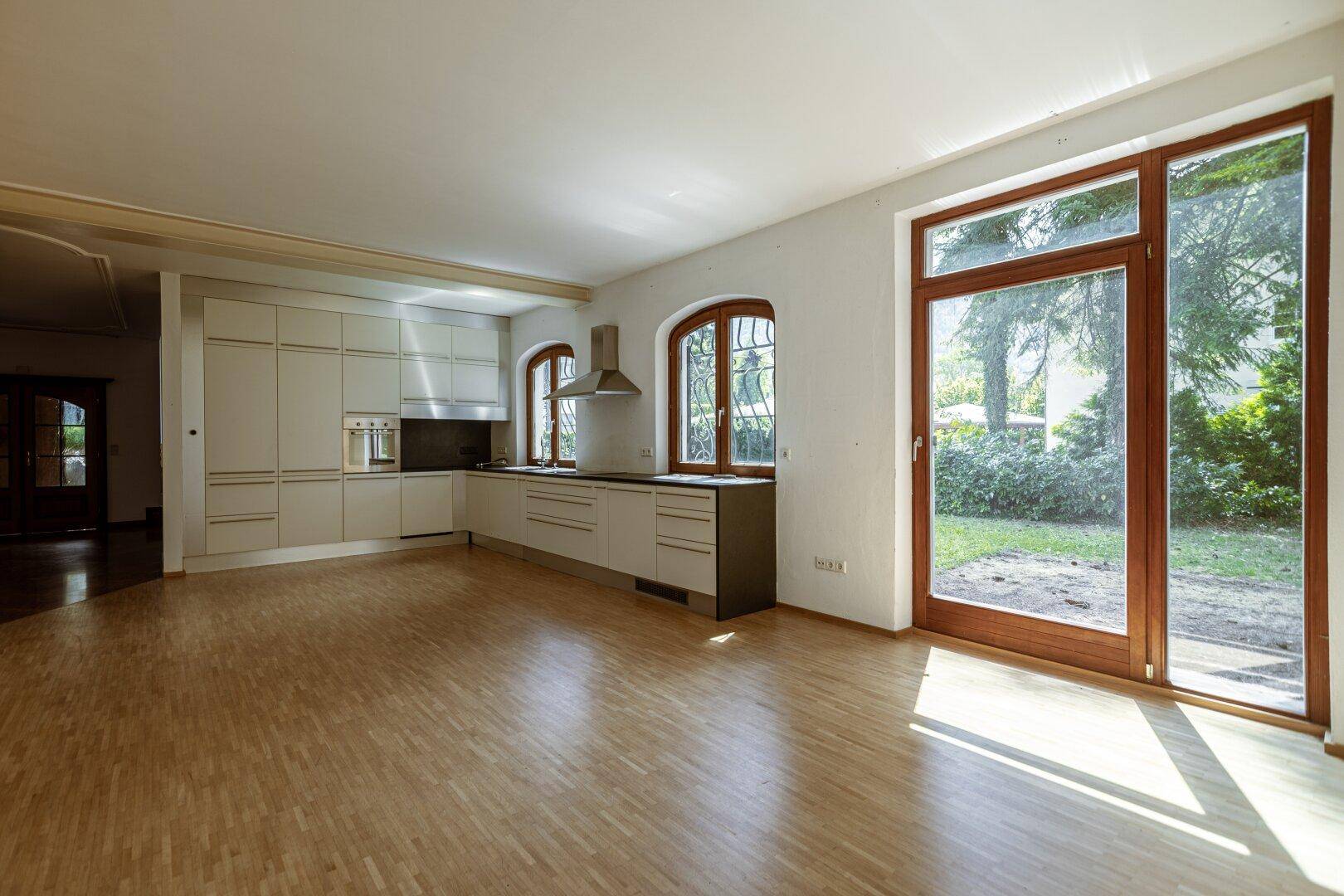 Moderne Einbauküche mit hellen Schränken, Holzfußboden und Zugang zum Garten.