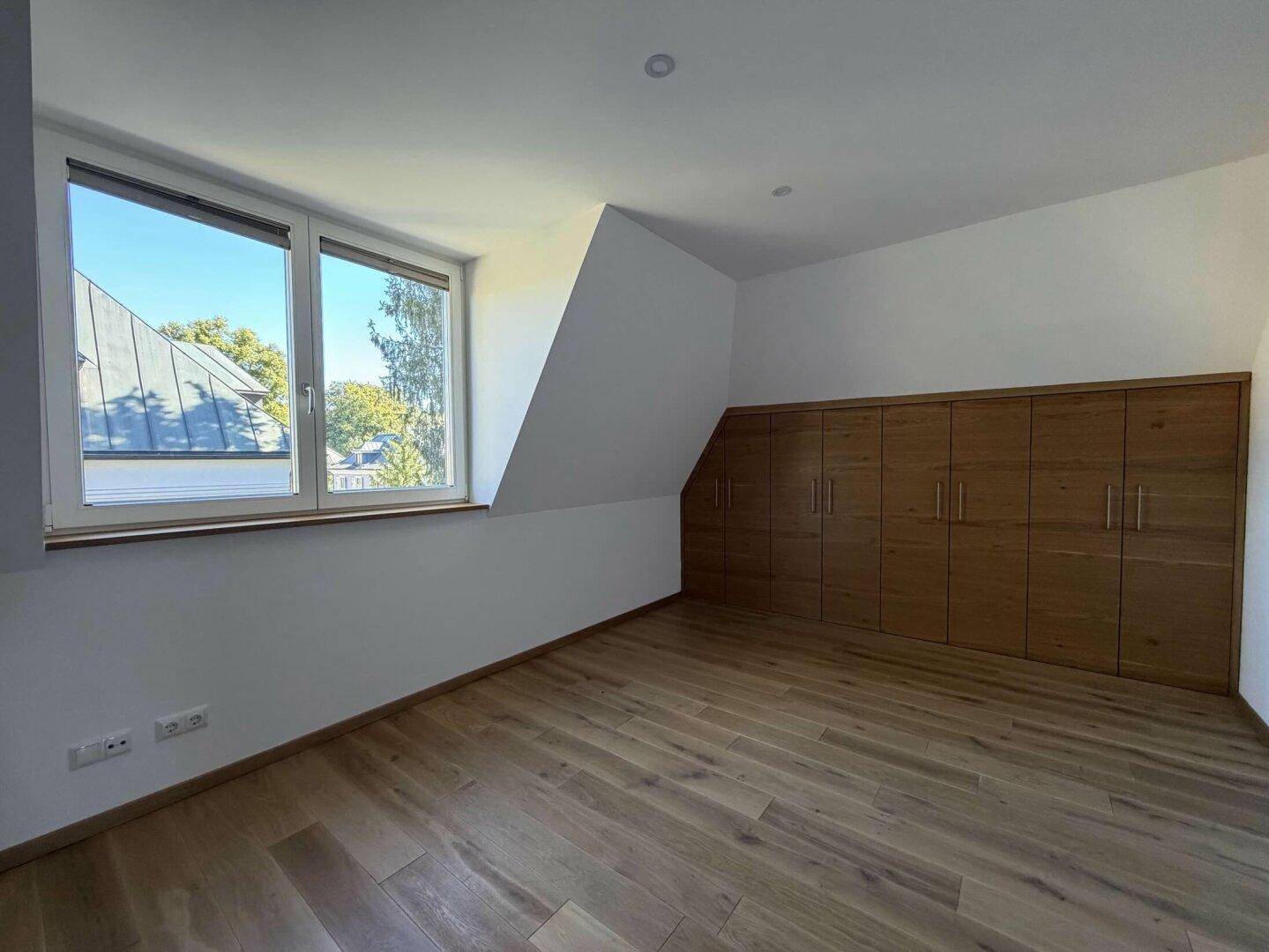 Schlafzimmer mit Holzboden, Einbauschränken und Dachschräge.
