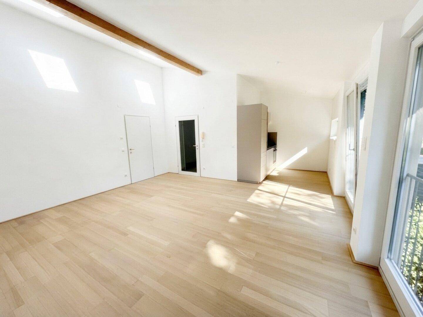 Offener Wohnbereich mit Holzboden, mehreren Dachfenstern und integrierter moderner Küchenzeile.