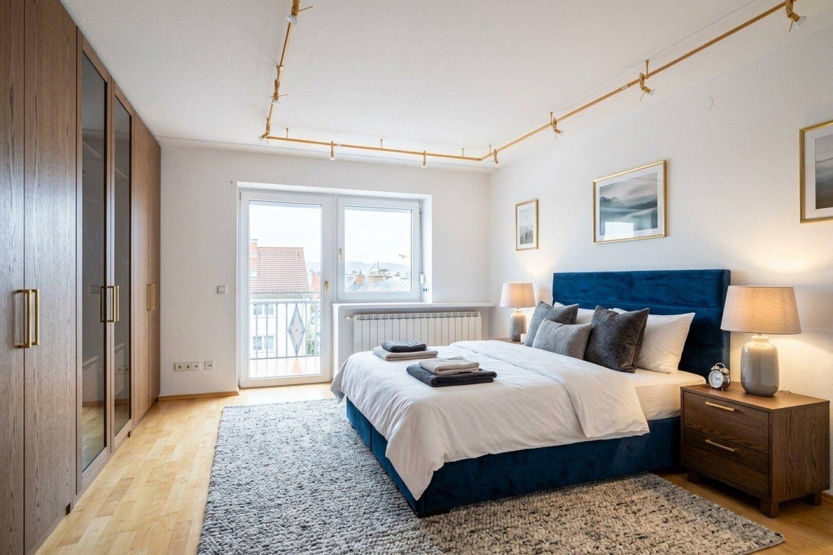 Komfortables Schlafzimmer mit Holzboden, Einbauschränken und direktem Zugang zu einem kleinen Balkon.