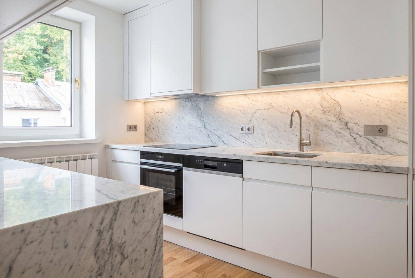 Moderne Küche mit weißen Schränken, eleganten Marmorarbeitsplatten und integrierten Geräten, hell und funktional.