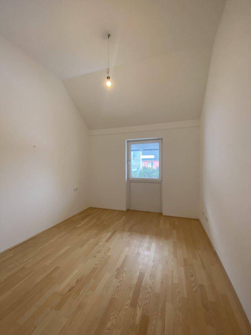 Geräumiges Schlafzimmer mit Holzboden und einem Fenster, das für ausreichend Tageslicht sorgt.