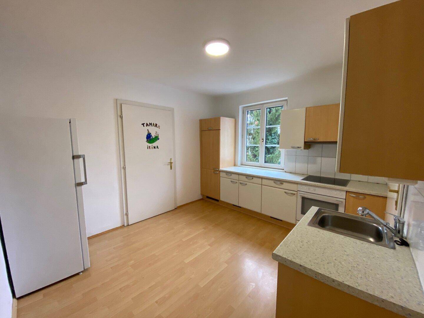 Funktionale Küche mit hellen Holzschränken, Spüle und Kühlschrank, bereit zur Nutzung.