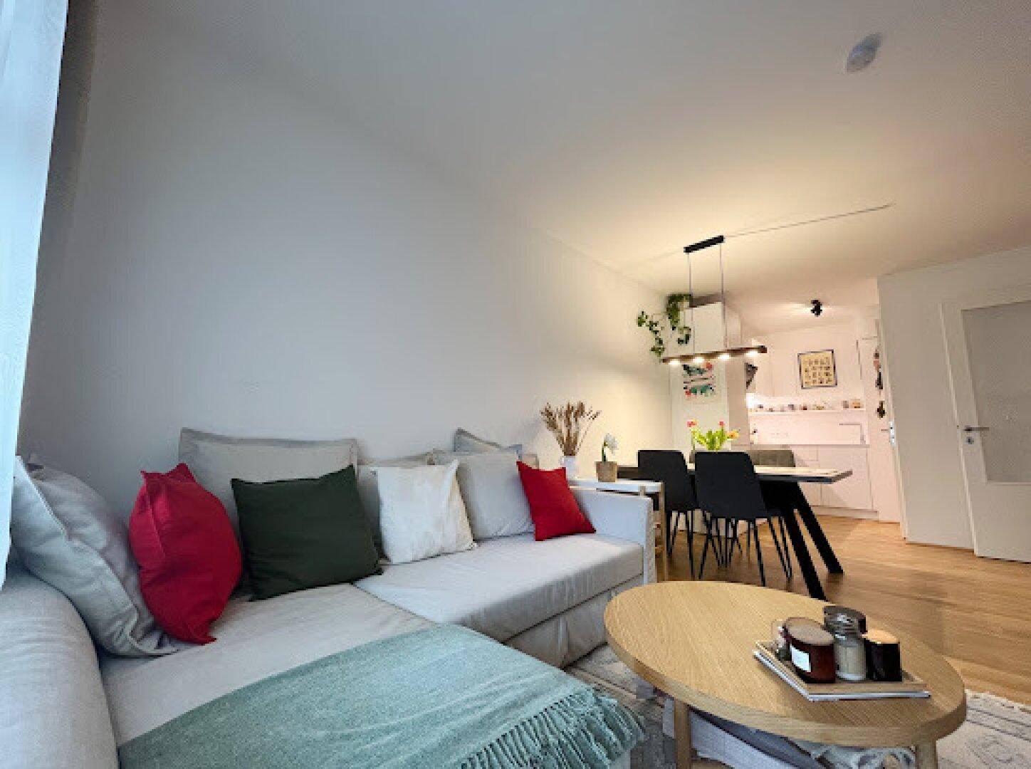 Gemütlicher Wohnbereich mit Sofa und Blick auf den Essbereich und die offene Küche.