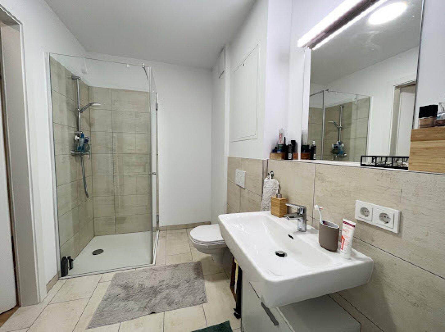 Modernes Badezimmer mit begehbarer Dusche, Wand-WC und Einzelwaschbecken.