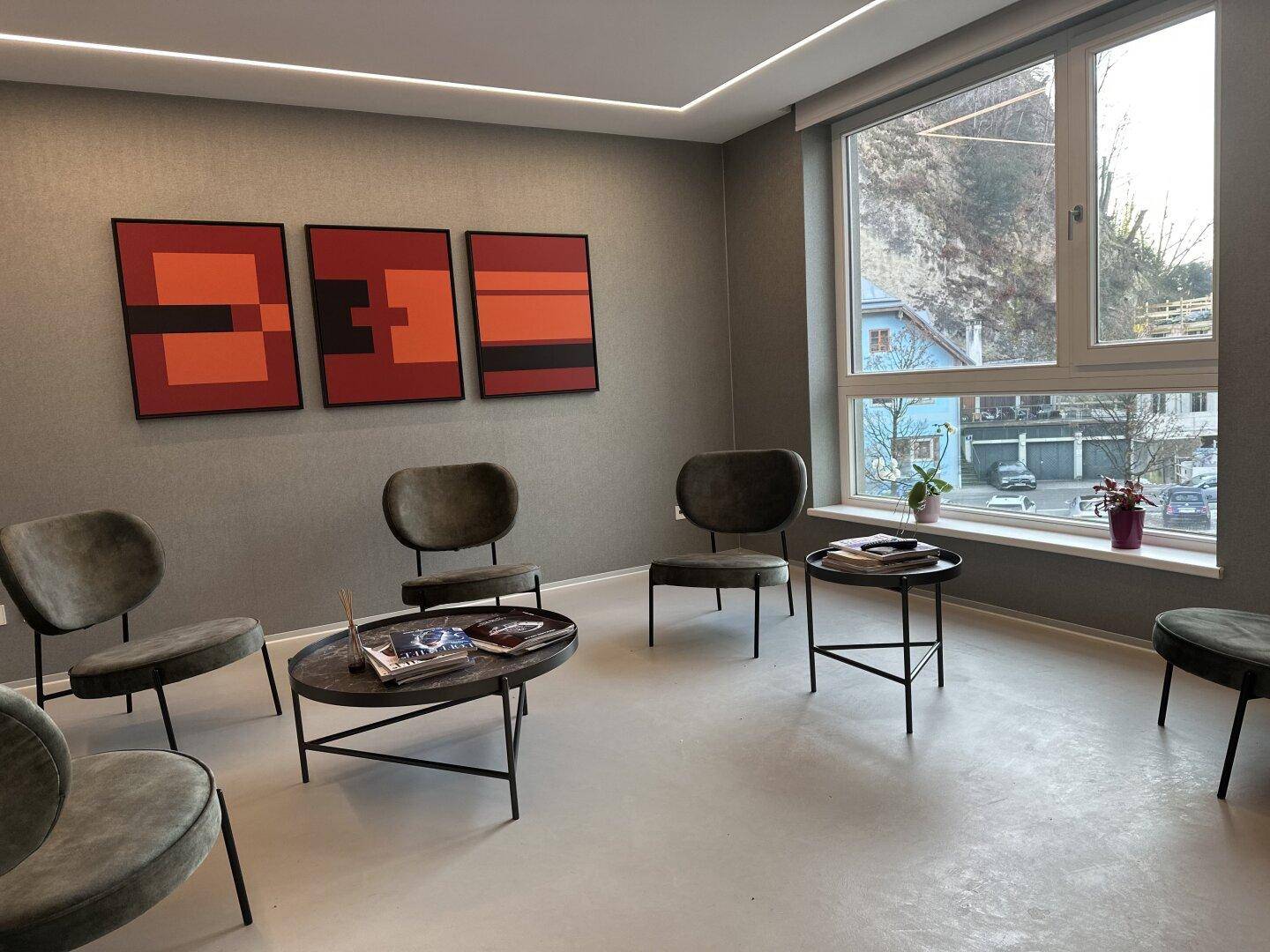 Heller Wartebereich mit bequemen Stühlen, modernen Kunstwerken und großen Fenstern mit Ausblick.