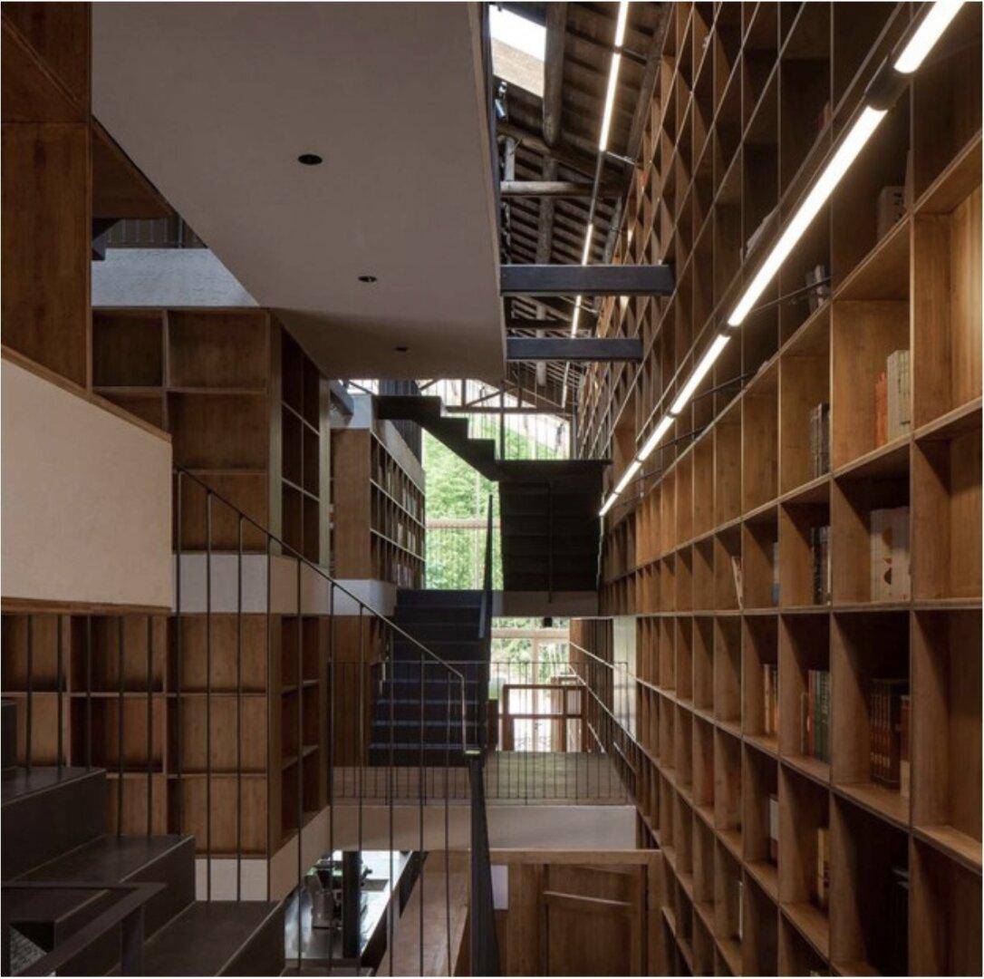 Mehrstöckiger Innenraum mit umfangreichen Holzregalen, Treppen und sichtbarer Deckenkonstruktion, beeindruckend.