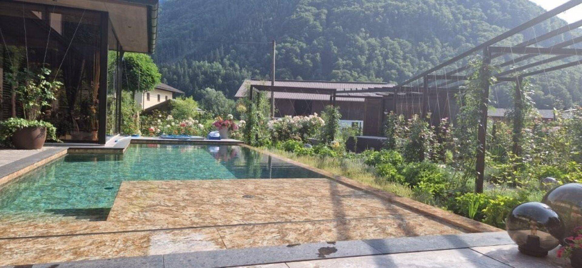 Großzügiger Poolbereich mit Liegeflächen und weitem Blick auf die bewaldeten Berge.
