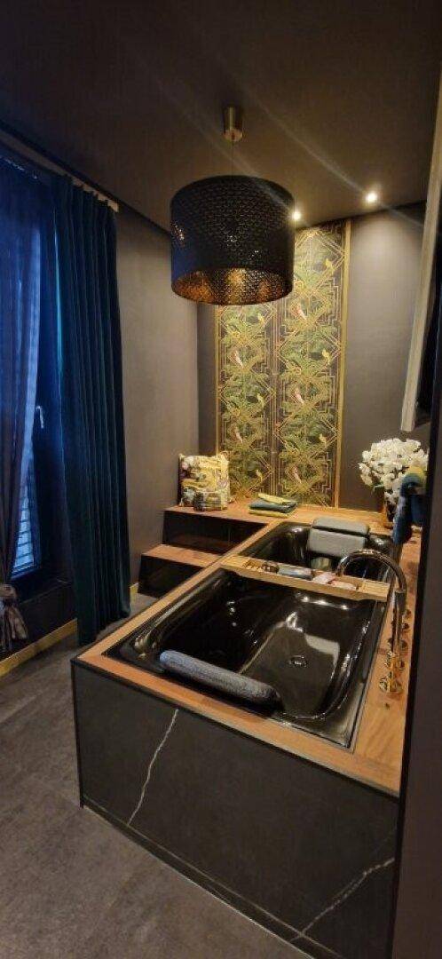 Exklusives Badezimmer mit großer schwarzer Badewanne und stilvoller Wandgestaltung.